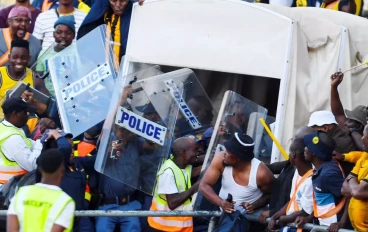 Police protect Kaizer Chiefs coach Arthur Zwane from fans throwing bottles during the DStv Premiership match between SuperSport United and Kaizer Chiefs at Royal Bafokeng Stadium